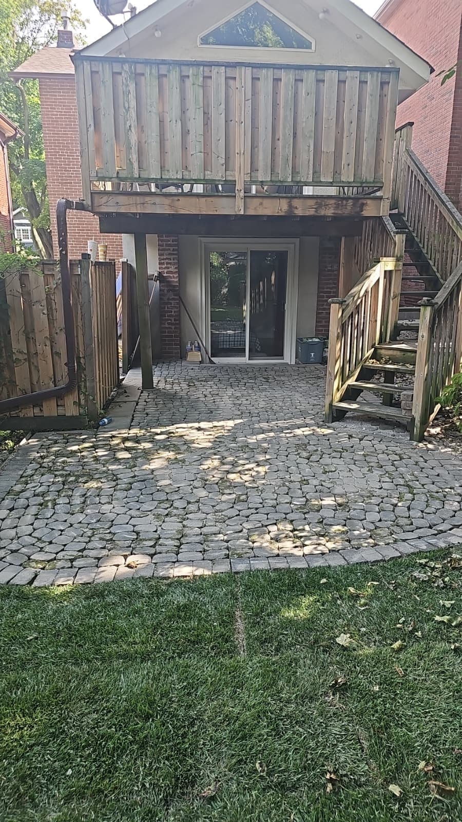 Cobblestone paver patio beside fresh sod at the house wall