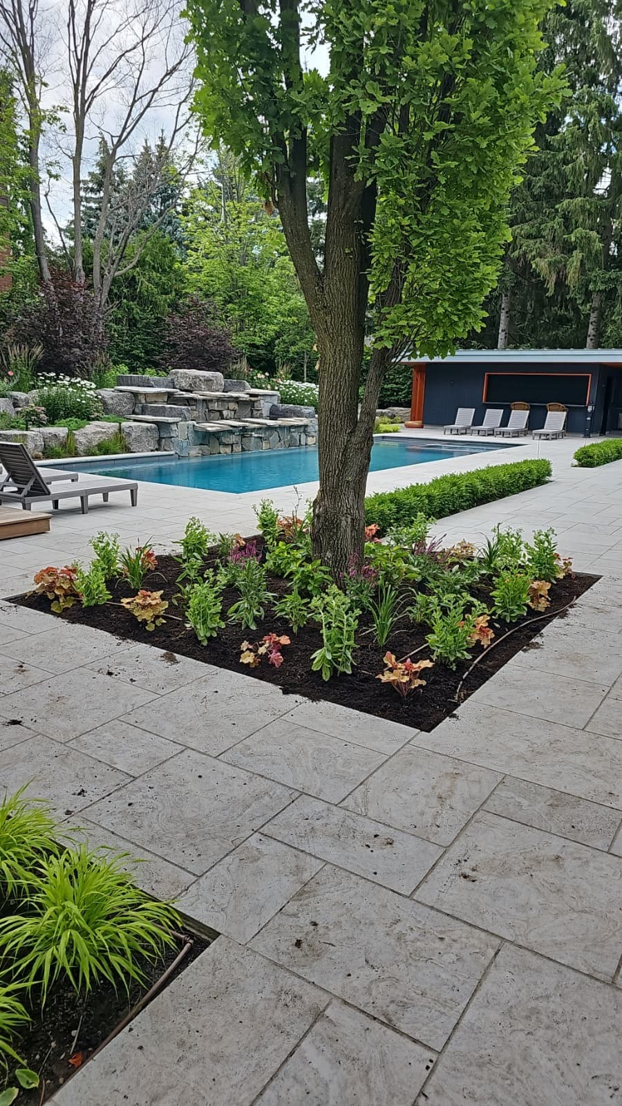 Large-format slab pool patio with an armour-stone waterfall wall in Richmond Hill
