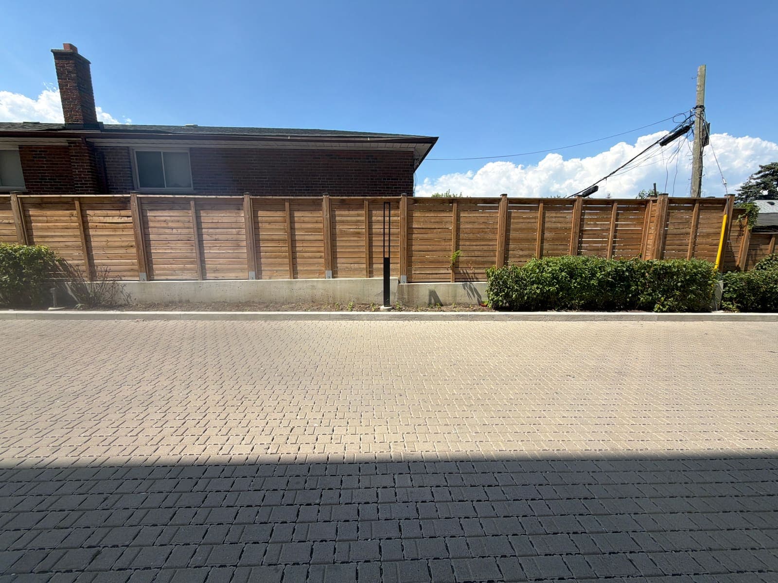 Wide permeable interlocking paver driveway with a cedar fence